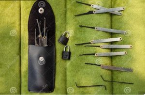 different tools used in lock picking arranged horizontally with two locks and a tools pouch