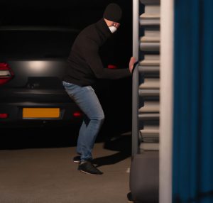 burglar entering through garage with car behind him and sliding the garage door